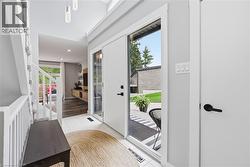 Bright entryway featuring a white door with full-length glass paneling, white tile flooring, and vaulted ceilings - 
