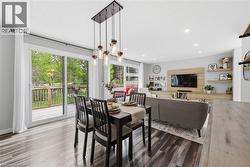 Open-concept living space featuring wood-finish flooring, recessed lighting, and a linear chandelier with glass jar pendants - 
