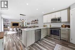 Modern kitchen featuring stainless steel appliances, two-tone cabinetry, and wood-finish flooring - 