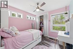 Room featuring wood-finish flooring, a ceiling fan with integrated lighting, and multiple windows - 