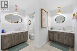 Dual vanity areas featuring wood-finish cabinetry, white countertops, and white subway tile backsplashes - 