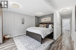 Bedroom featuring a dark wood-finish bed frame, light grey walls, and wood-finish flooring - 
