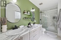 Bathroom featuring a dual vanity with undermount sinks, marble-look countertops, and matte black fixtures - 
