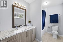 Bathroom featuring a vanity with a white-veined countertop, an undermount sink, and wood-finish cabinetry - 