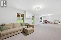 Spacious lower-level room featuring light-colored carpeting and white walls - 