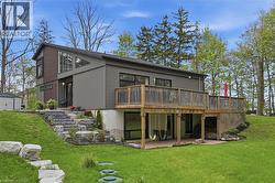 Contemporary multi-level residence featuring a large elevated wood deck, a covered patio area, and a stone-stepped pathway - 