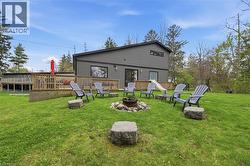 Expansive rear yard featuring a central fire pit, surrounding stone block seating, and a large wooden deck - 