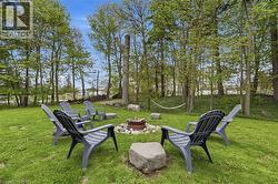 Manicured lawn with a stone-edged fire pit, surrounded by mature trees - 