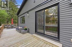 Spacious wooden deck with a wooden railing system, featuring grey horizontal siding and black-framed windows - 