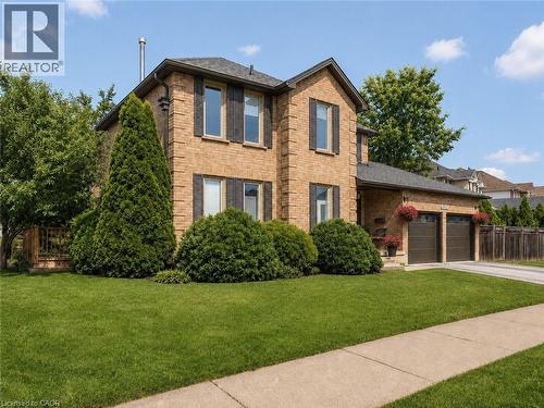 Two-story brick exterior with dark shutters, dual garage doors, and a paved driveway - 3311 Springvale Court, Burlington, ON - Outdoor