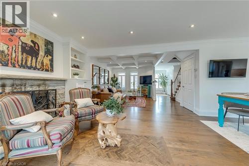 Living area featuring light wood-type flooring, coffered ceiling, a stone fireplace, recessed lighting, and ornamental molding - 3311 Springvale Court, Burlington, ON - Indoor Photo Showing Living Room With Fireplace