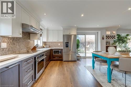 Two tone kitchen with dual tone cabinetry, stainless steel appliances, ornamental molding, light wood finished floors, and recessed lighting - 3311 Springvale Court, Burlington, ON - Indoor Photo Showing Kitchen With Upgraded Kitchen