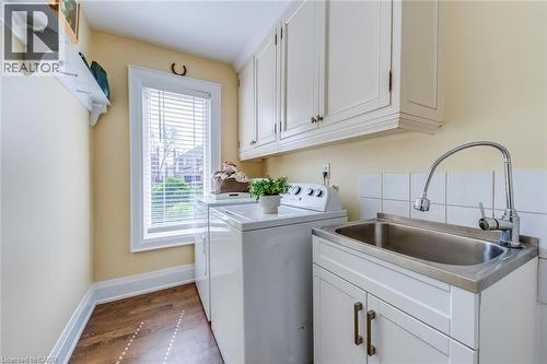 The laundry area features a stainless steel utility sink, white cabinetry, and a window providing natural light - 3311 Springvale Court, Burlington, ON - Indoor Photo Showing Laundry Room