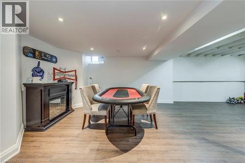 The property features a spacious room with light wood-style flooring, recessed lighting, and a window providing natural light - 3311 Springvale Court, Burlington, ON - Indoor