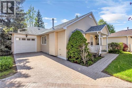 Single-story residence featuring light-colored siding, a covered front porch, and an attached garage - 375 Silverbirch Boulevard, Hamilton, ON - Outdoor