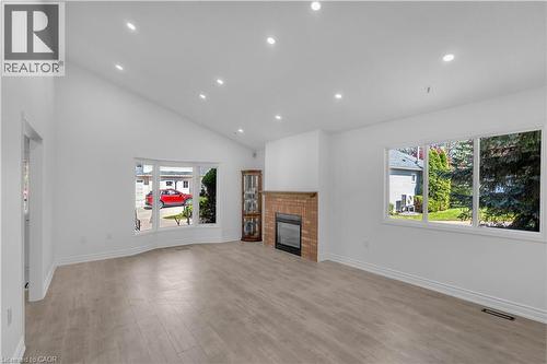 Spacious living area featuring wood-finish flooring, a brick-surround fireplace, and an angled ceiling with recessed lighting - 375 Silverbirch Boulevard, Hamilton, ON - Indoor Photo Showing Living Room With Fireplace
