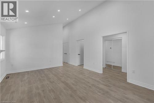 Spacious interior featuring wood-finish flooring, recessed lighting, white walls, and a vaulted ceiling - 375 Silverbirch Boulevard, Hamilton, ON - Indoor Photo Showing Other Room