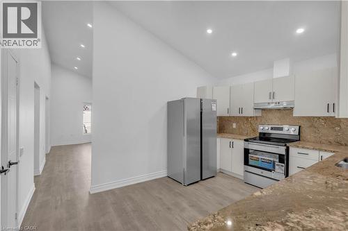 Contemporary kitchen featuring white cabinetry, stainless steel appliances, and stone countertops with a matching backsplash - 375 Silverbirch Boulevard, Hamilton, ON - Indoor Photo Showing Kitchen