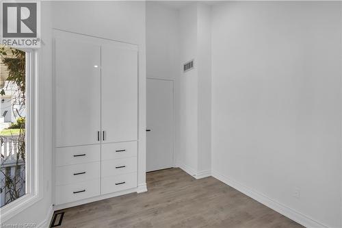 Integrated white cabinetry with black hardware, wood-finish flooring, and crisp white walls - 375 Silverbirch Boulevard, Hamilton, ON - Indoor Photo Showing Other Room