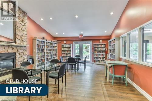 Community lounge with stone-clad fireplace and wood-finish flooring - 375 Silverbirch Boulevard, Hamilton, ON - Indoor With Fireplace