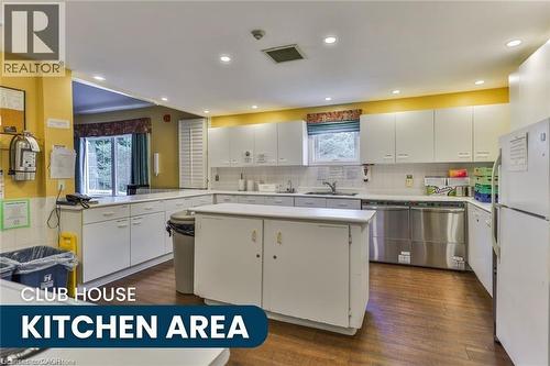 Spacious kitchen area featuring extensive white cabinetry, durable wood-finish flooring, recessed ceiling lighting, and a functional center island - 375 Silverbirch Boulevard, Hamilton, ON - Indoor Photo Showing Kitchen With Double Sink