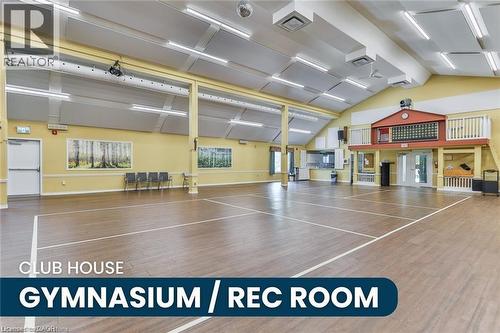 Spacious recreational hall featuring wood-finish flooring with court markings, a vaulted ceiling with acoustic paneling and integrated strip lighting, and a raised viewing area with a balcony - 375 Silverbirch Boulevard, Hamilton, ON - Indoor Photo Showing Other Room
