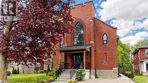 Red brick facade with arched windows, prominent front porch, concrete stairs, and mature landscaping - 41 Talbot Road, Delhi, ON - Outdoor