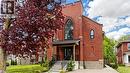 Red brick facade with arched windows, prominent front porch, concrete stairs, and mature landscaping - 41 Talbot Road, Delhi, ON  - Outdoor 