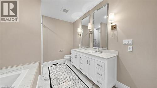 Double vanity with white cabinetry and chrome hardware, featuring two rectangular mirrors and sconce lighting - 41 Talbot Road, Delhi, ON - Indoor Photo Showing Bathroom