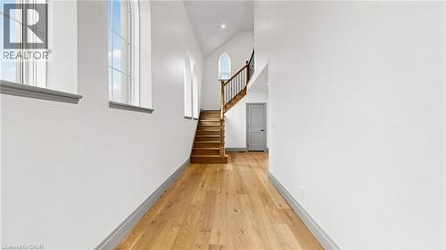 Vaulted ceilings with architectural windows, light wood-finish flooring, and a hardwood staircase with a wood and iron railing - 41 Talbot Road, Delhi, ON - Indoor Photo Showing Other Room