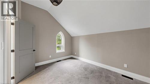 Vaulted ceiling room featuring a Gothic-style arched window, neutral wall paint, white trim, and gray carpet flooring - 41 Talbot Road, Delhi, ON - Indoor Photo Showing Other Room