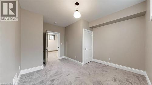 Spacious room featuring neutral wall tones, light gray patterned carpeting, white baseboards, and white interior doors with black hardware - 41 Talbot Road, Delhi, ON - Indoor Photo Showing Other Room