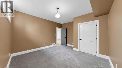 Carpeted room featuring a single-panel interior door, a two-panel interior door, a ceiling-mounted light fixture, and baseboard trim - 41 Talbot Road, Delhi, ON - Indoor Photo Showing Other Room