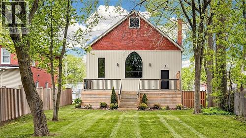 Rear exterior featuring a red brick gable, arched window, and horizontal cream siding - 41 Talbot Road, Delhi, ON - Outdoor