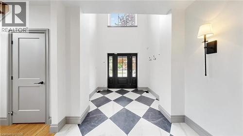 Grand foyer featuring a black and white checkerboard tile floor, soaring ceilings, a transom window, and a dark paneled front door with glass inserts - 41 Talbot Road, Delhi, ON - Indoor Photo Showing Other Room
