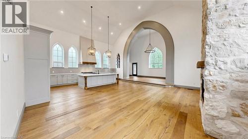 Spacious open-concept interior featuring light wood-finish flooring, a stone-clad fireplace, and a kitchen with an oversized island, light cabinetry, and arched windows - 41 Talbot Road, Delhi, ON - Indoor