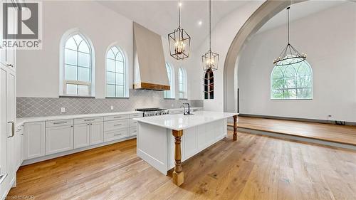 Spacious kitchen and living area featuring arched windows, high vaulted ceilings, hardwood flooring, a large kitchen island with a stone countertop, and an integrated range hood with wood accents - 41 Talbot Road, Delhi, ON - Indoor Photo Showing Kitchen