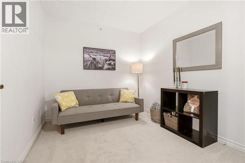 Carpeted room with white walls, featuring a dark brown shelving unit and a framed mirror - 1411 Walker'S Line Unit# 105, Burlington, ON - Indoor