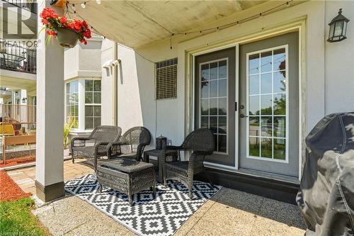 Covered patio with a bay window, concrete flooring, and a sliding glass door with grid-patterned panels - 1411 Walker'S Line Unit# 105, Burlington, ON - Outdoor With Deck Patio Veranda With Exterior