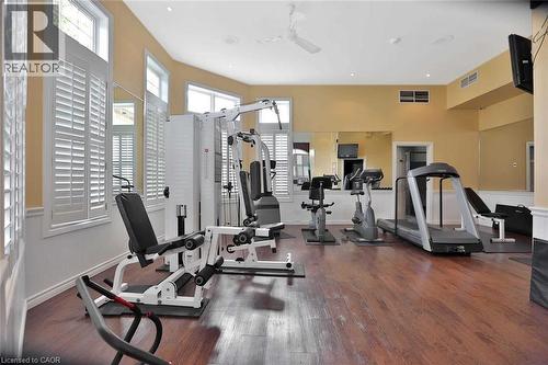 Dedicated fitness space featuring wood-finish flooring, multiple windows with white plantation shutters, and a ceiling fan - 1411 Walker'S Line Unit# 105, Burlington, ON - Indoor Photo Showing Gym Room