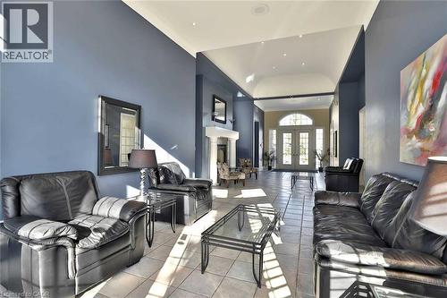 Grand entry foyer featuring light-toned tile flooring, tall ceilings with recessed lighting, and a white arched double-door entry with transom window - 1411 Walker'S Line Unit# 105, Burlington, ON - Indoor Photo Showing Living Room