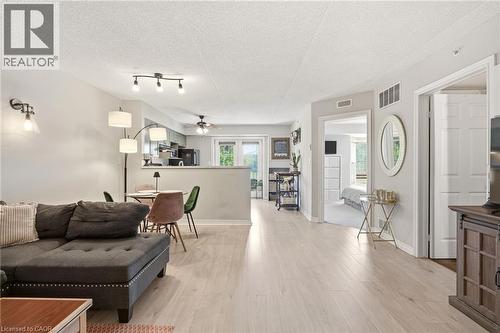 Open-concept living area featuring wood-finish flooring, recessed lighting, and a kitchen pass-through - 1411 Walker'S Line Unit# 105, Burlington, ON - Indoor Photo Showing Living Room