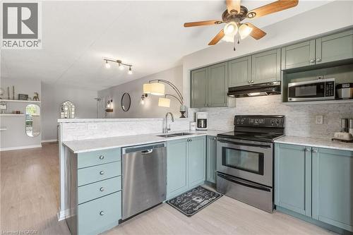 Kitchen featuring light blue cabinetry, light-toned countertops, and a full stainless steel appliance suite - 1411 Walker'S Line Unit# 105, Burlington, ON - Indoor Photo Showing Kitchen