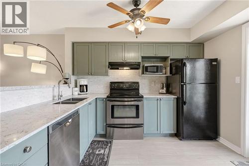 Kitchen featuring light-colored wood-finish flooring, light-toned countertops, and a white tile backsplash - 1411 Walker'S Line Unit# 105, Burlington, ON - Indoor Photo Showing Kitchen With Double Sink