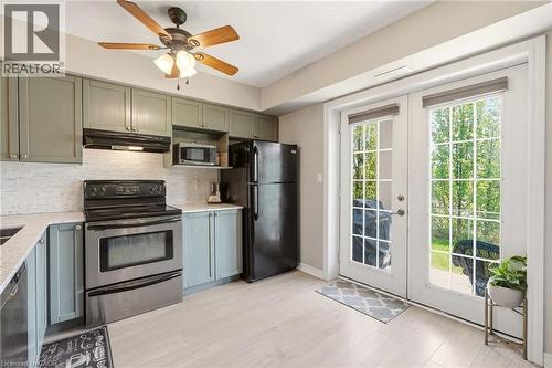 Kitchen featuring light green and blue-grey cabinetry, stainless steel appliances, and a light-toned backsplash - 1411 Walker'S Line Unit# 105, Burlington, ON - Indoor Photo Showing Kitchen