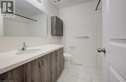 Bathroom featuring a wood-finish vanity with an integrated sink and chrome faucet, a coordinating wall-mounted storage cabinet, and white tile flooring - 