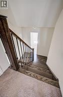 Staircase featuring wood-finish treads, iron balusters, and a rich wood-finish handrail - 