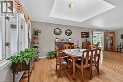 Dining area featuring wood-finish flooring, a recessed ceiling with a central light fixture, and crown molding - 