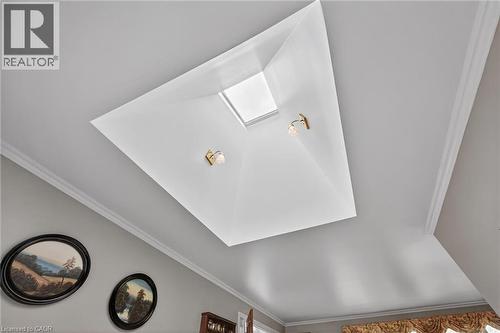 Ceiling featuring a recessed skylight, two wall sconces with brass-finish accents, and crown molding - 2 Summit Circle, Simcoe, ON - Indoor Photo Showing Other Room
