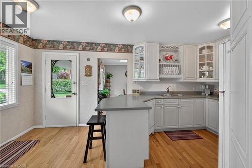 Kitchen featuring wood-finish flooring, white cabinetry, and a peninsula with countertop seating - 2 Summit Circle, Simcoe, ON - Indoor Photo Showing Kitchen With Double Sink